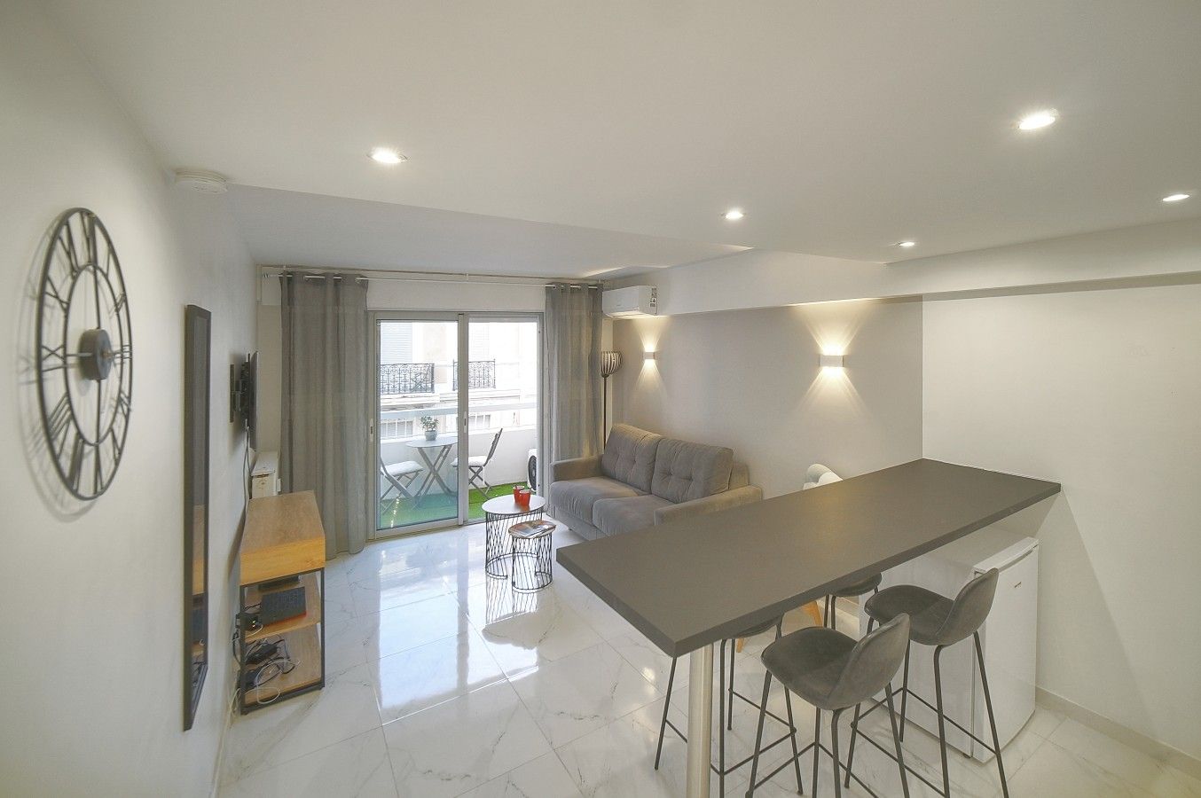 Eine moderne Wohnung mit Essbereich, einer Couch und einem Balkon mit Tisch und Stühlen.
