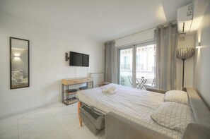 Una camera d'hotel moderna con un letto, una TV, una scrivania e un balcone con vista.