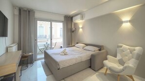 Ein modernes Hotelzimmer mit Bett, Stuhl, Schreibtisch und Balkon.