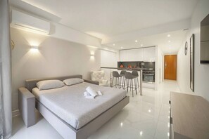 Quarto de hotel moderno com uma cama grande, uma kitchenette pequena e um espaço de refeições.