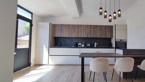 Eine moderne Küche mit Essbereich, Holzschränken, einer schwarzen Arbeitsplatte und Pendelleuchten.