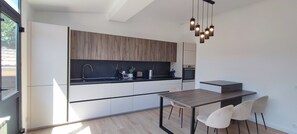 A modern kitchen with a dining area, featuring a wooden countertop, a built-in oven, and a hanging light fixture. - Two-bedroom apartment in France, Vallauris (Vallauris)
