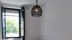 Ein modernes Wohnzimmer mit großem Fenster, einer Couch, einem kleinen runden Tisch und einer Pendelleuchte.