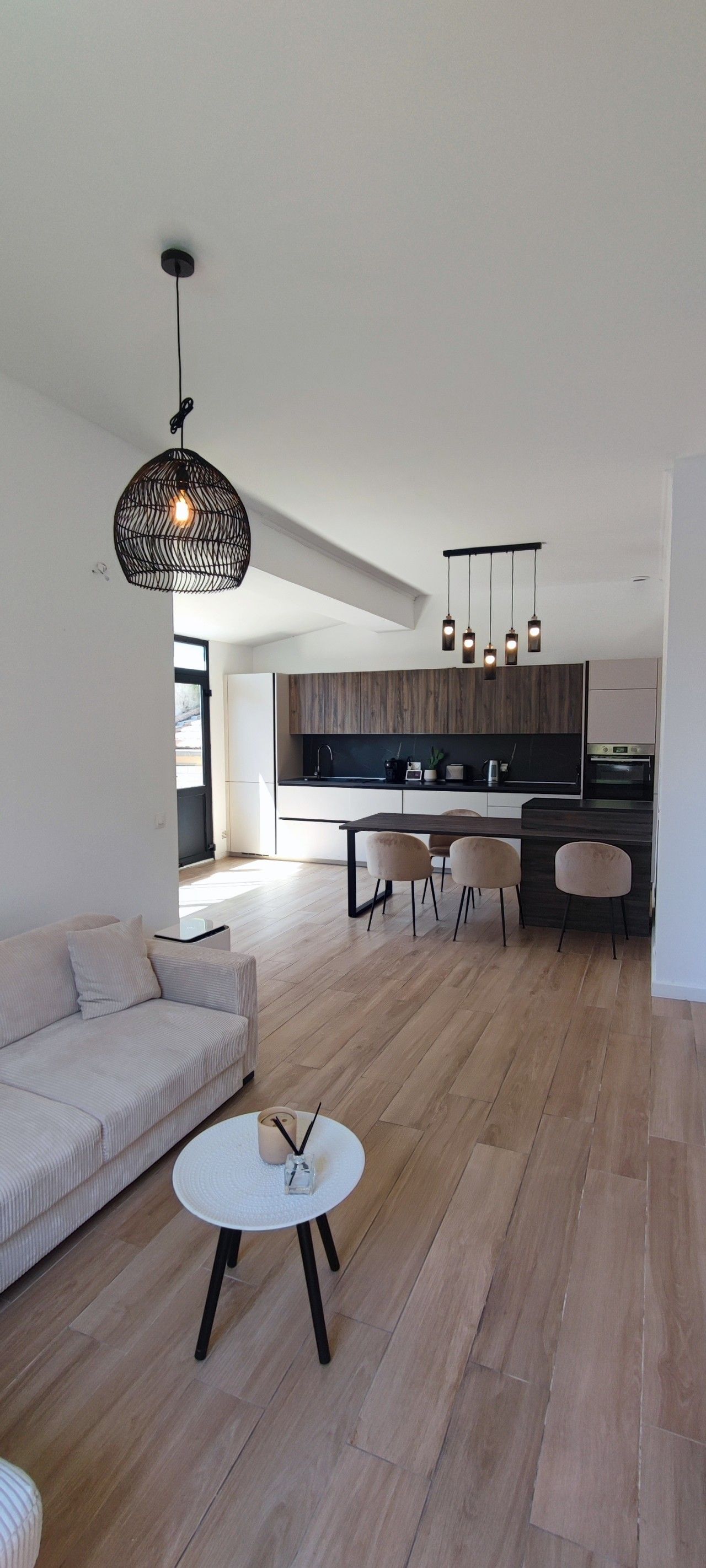 Un salon moderne avec un canapé, une table basse ronde et un coin repas avec des chaises.