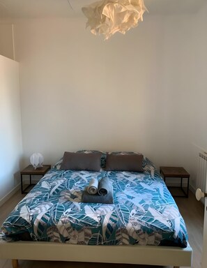 A bedroom with a bed, pillows, a rolled towel, a nightstand, and a lamp. - Two-bedroom apartment in France, Vallauris (Vallauris)