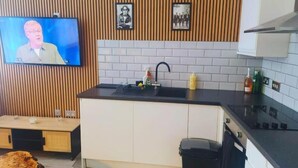 A modern kitchen with a wooden wall panel, a flat-screen TV, a sink, and a stove. - Heritage Bank Liverpool near Cavern (Liverpool)