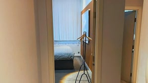 A bedroom with a bed, a standing lamp, and a window with blinds. - Heritage Bank Liverpool near Cavern (Liverpool)