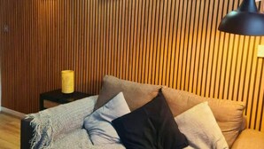 A room with a wooden slat wall, a sofa with patterned cushions, a small side table, and a lamp. - Heritage Bank Liverpool near Cavern (Liverpool)