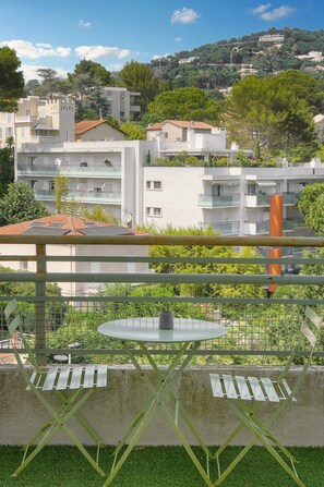 A terrace with a table and chairs, overlooking a residential area with buildings and greenery. - 12251546 FRGK Isola Bella ` 2-room, high-speed Wi-Fi, air conditioning ` (Cannes)