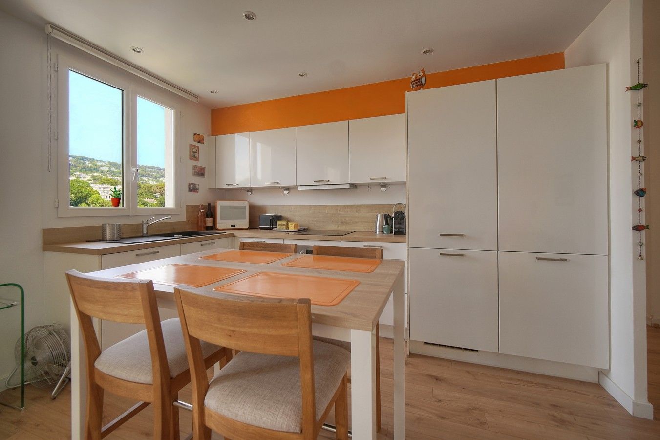 Una cocina moderna con armarios blancos, una mesa de comedor de madera y sillas.