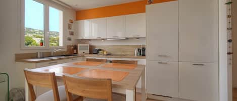 Una cocina moderna con armarios blancos, una mesa de comedor de madera y sillas.