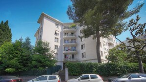 A multi-story residential building with balconies, parked cars, and surrounding greenery. - FRGK Isola Bella Comfortable apartment (Cannes)