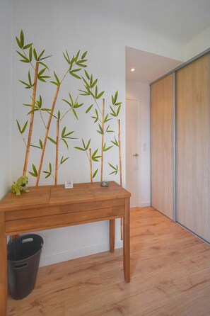 A room with a wooden table, a black trash bin, and a wall with bamboo decoration. - 12251546 FRGK Isola Bella ` 2-room, high-speed Wi-Fi, air conditioning ` (Cannes)