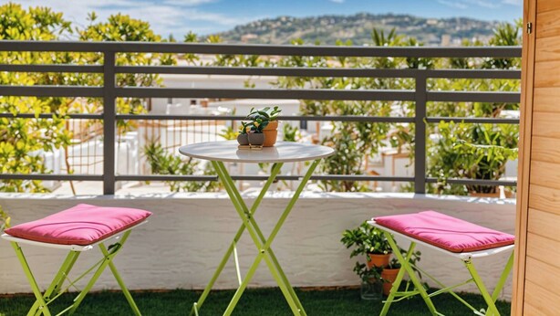 A balcony with a round table, two chairs, and potted plants. - FRGK Isola Bella Comfortable apartment (Cannes)