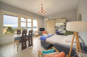 Un dormitorio con cama, escritorio, silla, televisión y vistas al exterior.