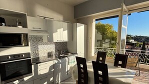 Eine moderne Küche mit weißen Schränken, einem eingebauten Backofen und einem Essbereich mit Tisch und Stühlen.
