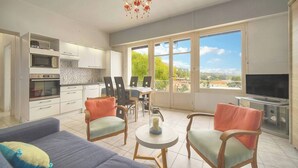 Eine moderne Küche mit integrierten Geräten, einem Essbereich mit Stühlen, einer Couch und einem Fernseher.