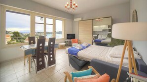 Ein Schlafzimmer mit Bett, Schreibtisch, Stühlen, Fernseher, Spiegel und Blick ins Freie.