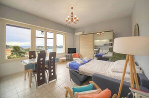 Ein Schlafzimmer mit Bett, Schreibtisch, Stühlen, Fernseher, Spiegel und Blick ins Freie.