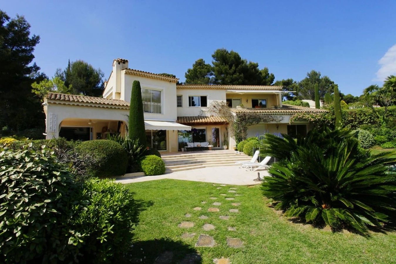 A two-story house with a covered patio and a well-maintained garden.