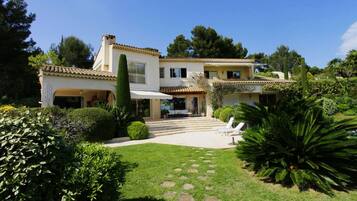 A two-story house with a covered patio and a well-maintained garden.