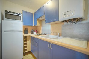 Eine kleine Küche mit Kühlschrank, Mikrowelle, Spüle und Schränken.