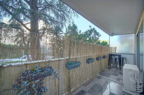 A covered outdoor area with a bamboo fence, potted plants, and a small table with chairs. - 13107732 Frgk Tamaris Antibes Terrace: Air Conditioning & Ultra-Fast Wi-Fi (Antibes)