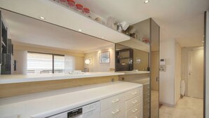 A modern kitchen with white cabinetry, a dishwasher, and a large mirror. - ATHENA (Cannes)