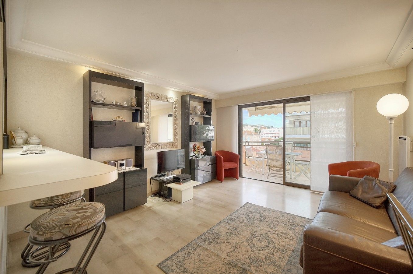 Ein modernes Wohnzimmer mit einer Couch, einem Couchtisch, einem Fernseher und einem Balkon mit Blick.