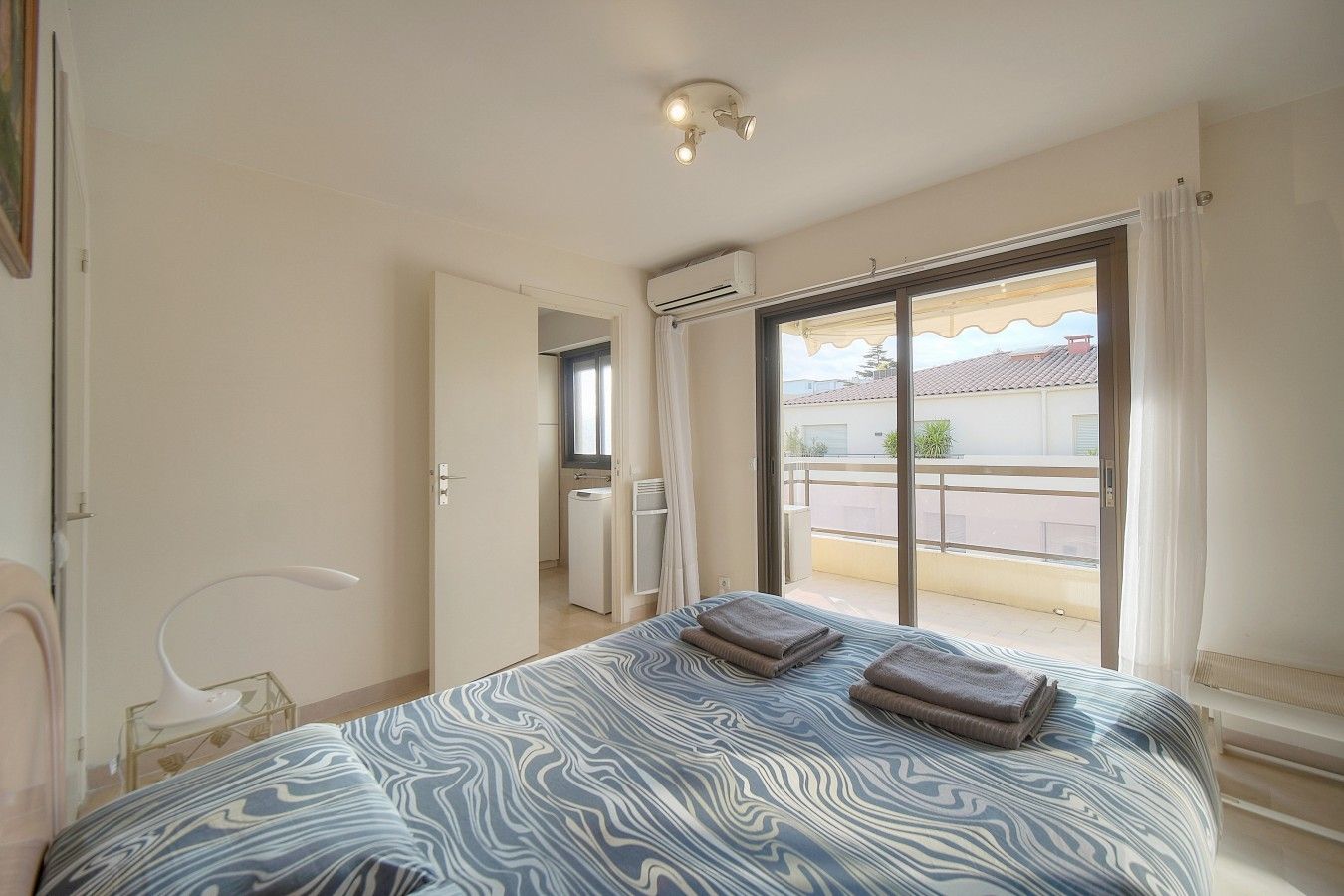 Quarto com cama, abajur, janela com vista para o exterior e ar condicionado.
