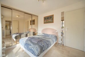 Ein Schlafzimmer mit einem großen Bett, einem Nachttisch, einem Spiegel und einem Bild an der Wand.