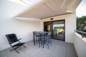 A balcony with a table and chairs, a folding chair, and a glass door leading to an outdoor seating area. - One-bedroom apartment in Antibes, France (Antibes)