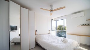 Quarto com uma cama, ventilador de teto, janela e espelho.