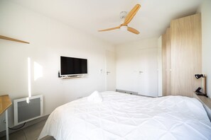 A bedroom with a bed, a ceiling fan, a TV, and a wardrobe. - One-bedroom apartment in Antibes, France (Antibes)