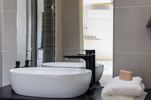 A modern bathroom with a large white sink, a black faucet, and a mirror reflecting a shower area. - One-bedroom apartment in Antibes, France (Antibes)
