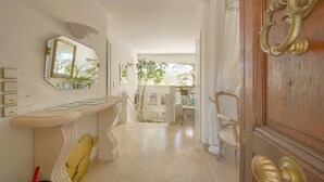 A hallway with a white wall, a mirror, a door with a brass handle, and a staircase leading to another room. - VILLA MÉVANIA antibes (Antibes)