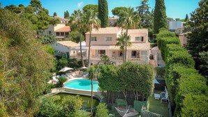 A multi-story building with a swimming pool, surrounded by lush greenery and palm trees. - VILLA MÉVANIA antibes (Antibes)
