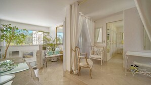 A room with a dining table, chairs, a chair with a canopy, a mirror, and a view of the outdoors. - VILLA MÉVANIA antibes (Antibes)
