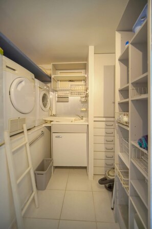 A compact laundry room with a washing machine, dryer, sink, and storage shelves. - Nine-bedroom home in France, Antibes (Antibes)