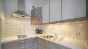 A modern kitchen with a stainless steel sink, a built-in range, and grey cabinetry. - LE CLEMENCEAU (Cannes)
