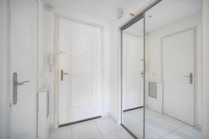 A hallway with white doors, a visible intercom, and a tiled floor. - 15433974 FRGK Elegant Studio CLEMENCEAU Terrace (Cannes)