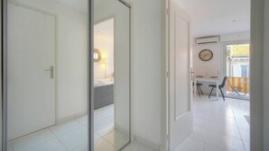 A modern interior with a sliding door, a bed, a desk with chairs, and a clock on the wall. - LE CLEMENCEAU (Cannes)