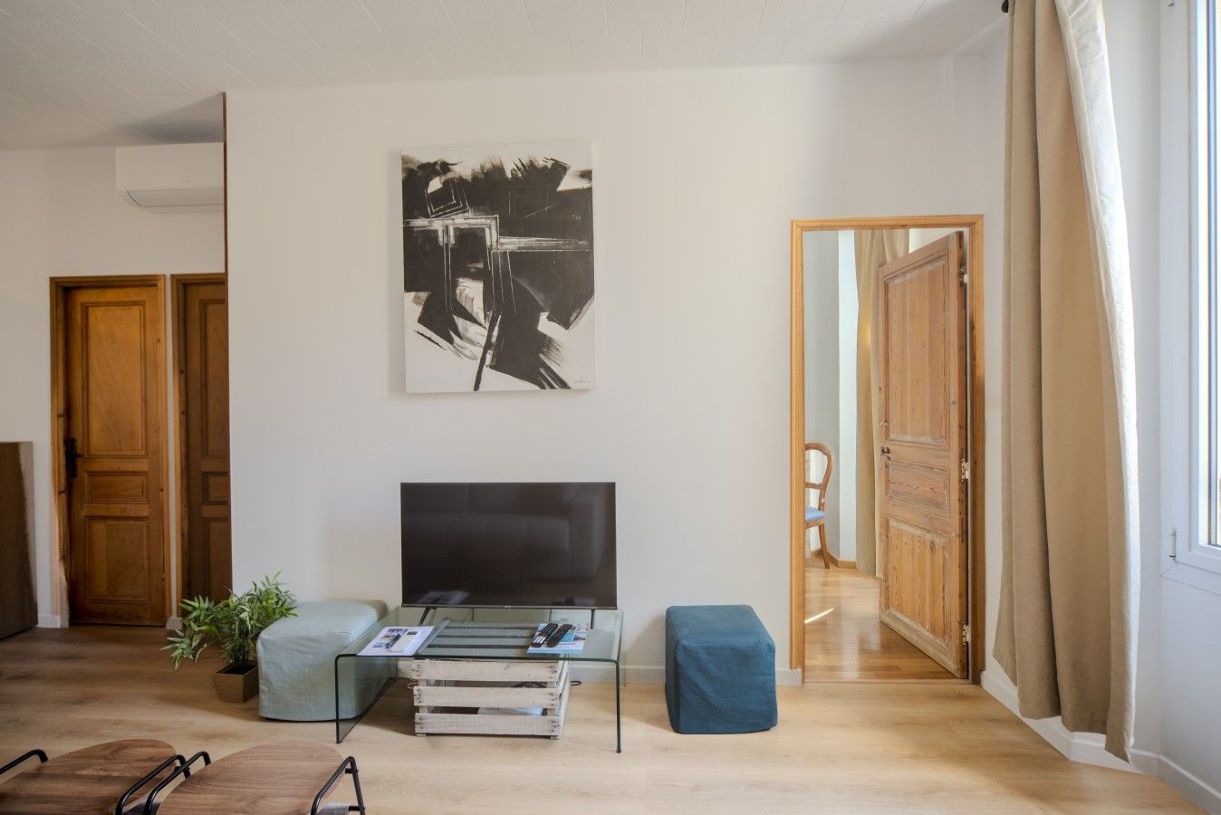 Una sala de estar con televisión de pantalla plana, una mesa de centro, un sofá y un cuadro en la pared.