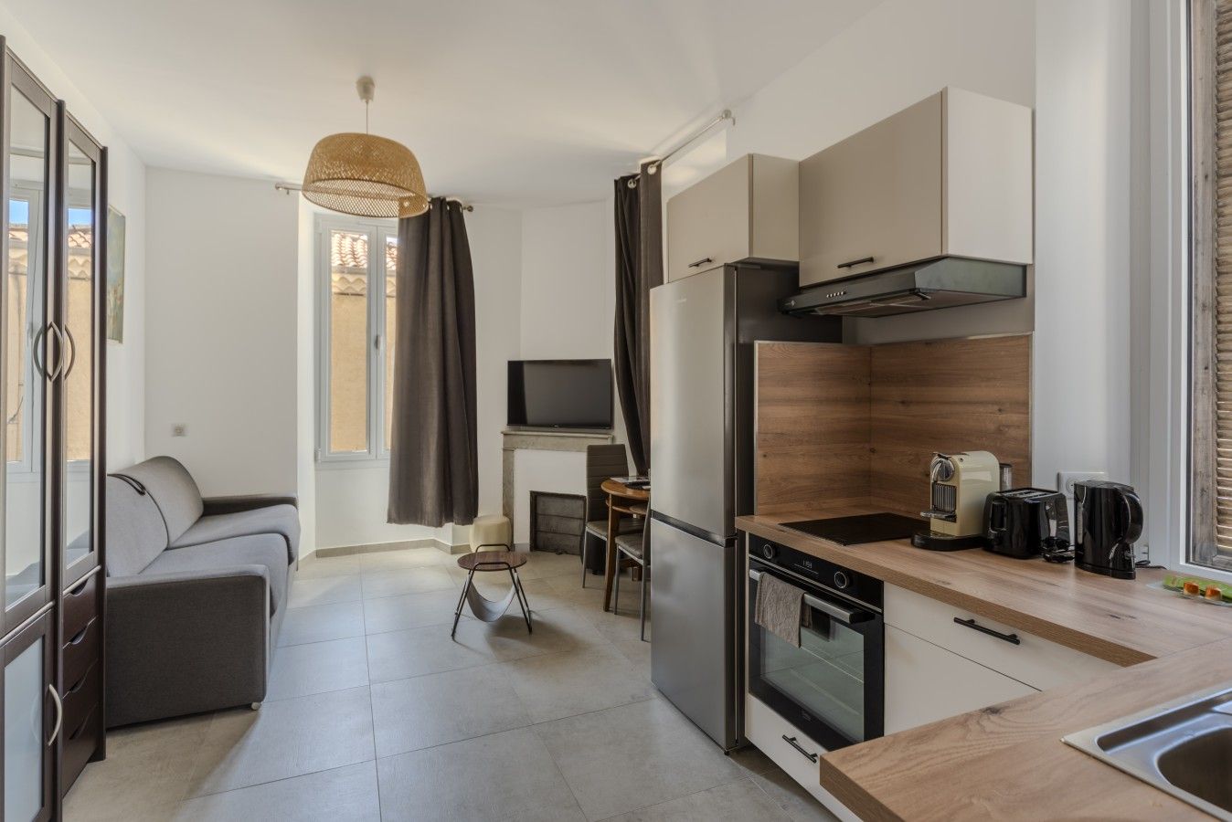 A compact living space with a kitchenette, a sofa, a television, and a dining area.
