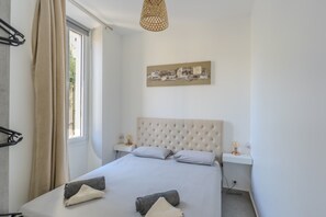 A bedroom with a large bed, a window with curtains, a bedside table with a lamp, and a wall-mounted artwork. - Three-bedroom apartment in France, Cannes (Cannes)
