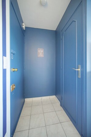A hallway with blue walls, a white ceiling, and a tiled floor. - FRGK - Copacabana Palm Beach Studio (Cannes)