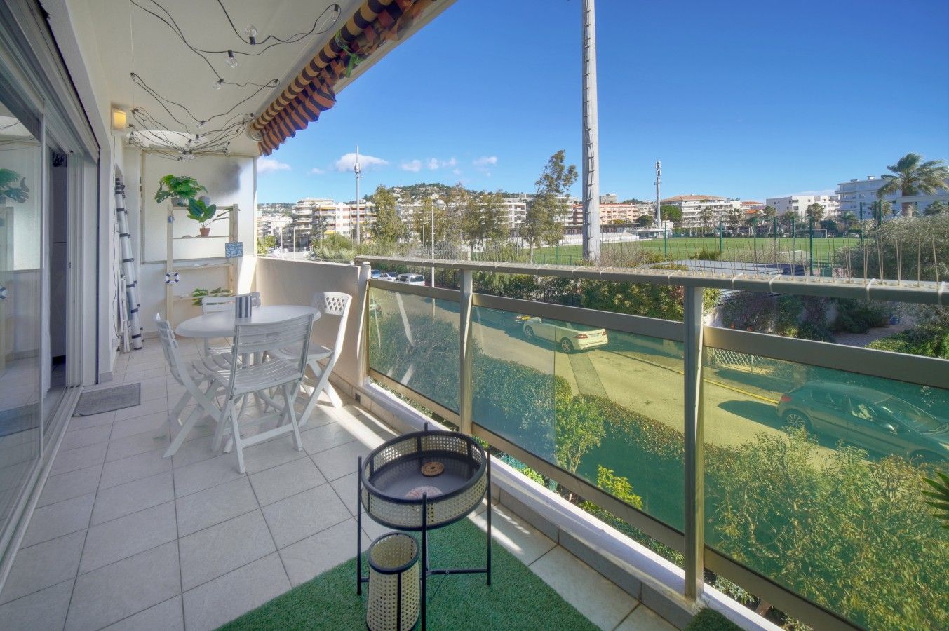 A balcony with a view of a golf course, a table and chairs, and a small round table.