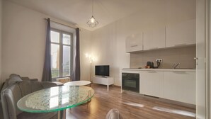 Eine moderne Küche mit weißen Schränken, einem Einbauofen und einem Essbereich mit einem Glastisch und grauen Stühlen.