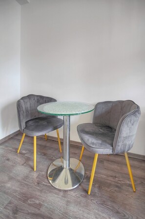 A small room with a round glass table and two grey upholstered chairs with yellow legs. - 15239747 FRGK 1-Bedroom Design 300m Palais & Beach Apartment (Cannes)