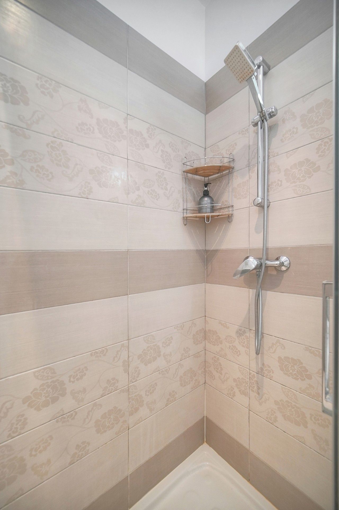 Eine Dusche mit Handbrause und Wandarmatur.
